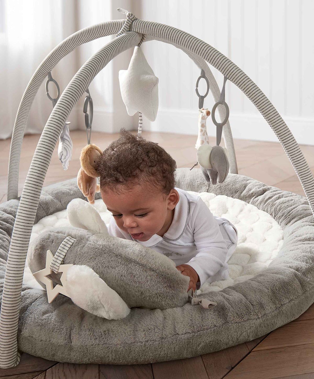 Elephant playmat gym with arch and dangling plush toys, child playing on gray cushion