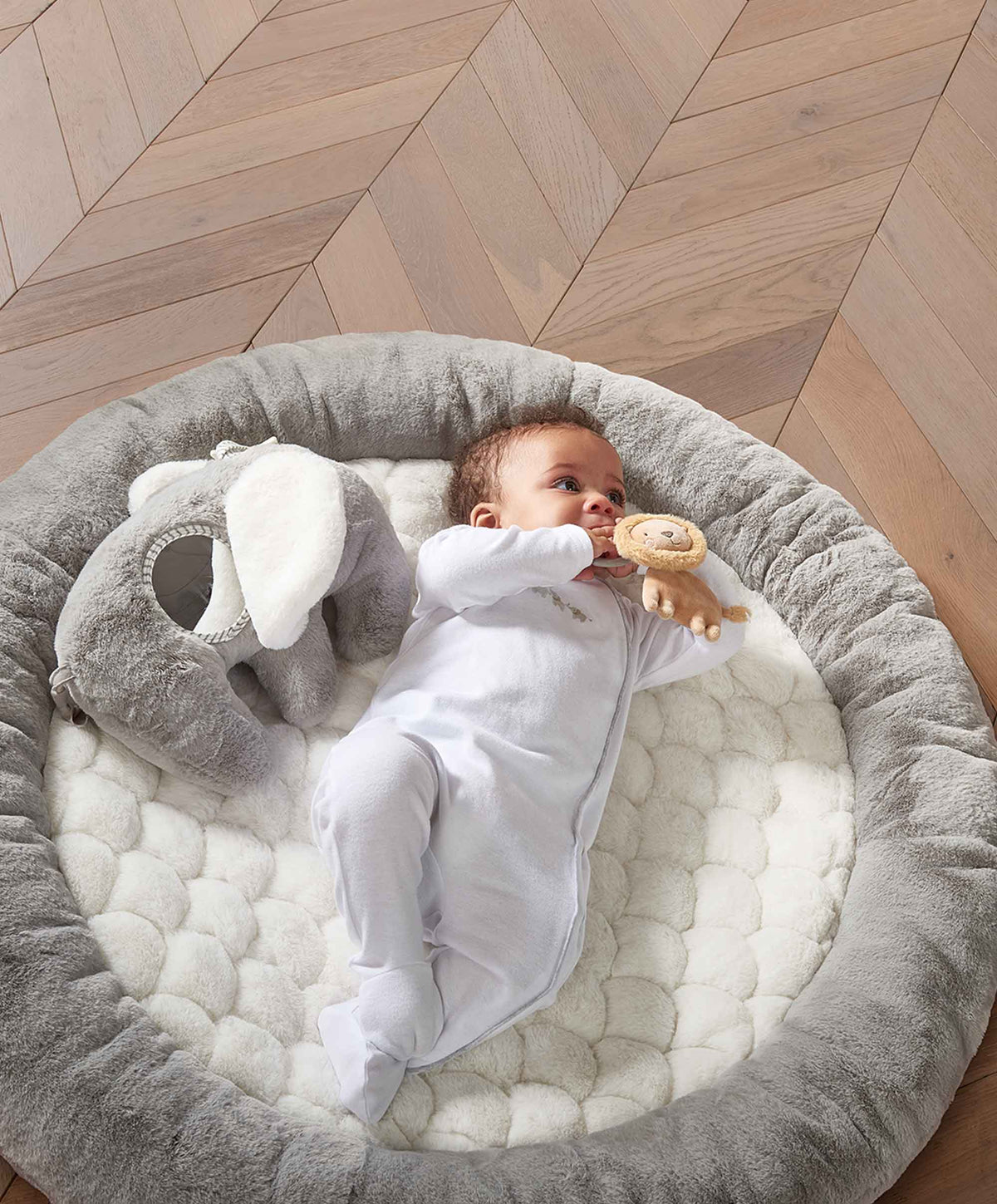 Elephant playmat gym with gray cushioned mat and plush elephant beside baby on it