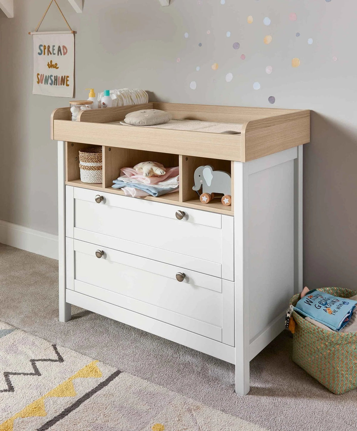 White nursery dresser changer with light wood top, open shelf, and three drawer fronts