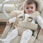 Beige baby bouncer seat in use, infant wearing white sleeper with small animal motifs
