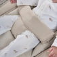 Beige bouncer harness close-up with white sleeper featuring tiny animal prints