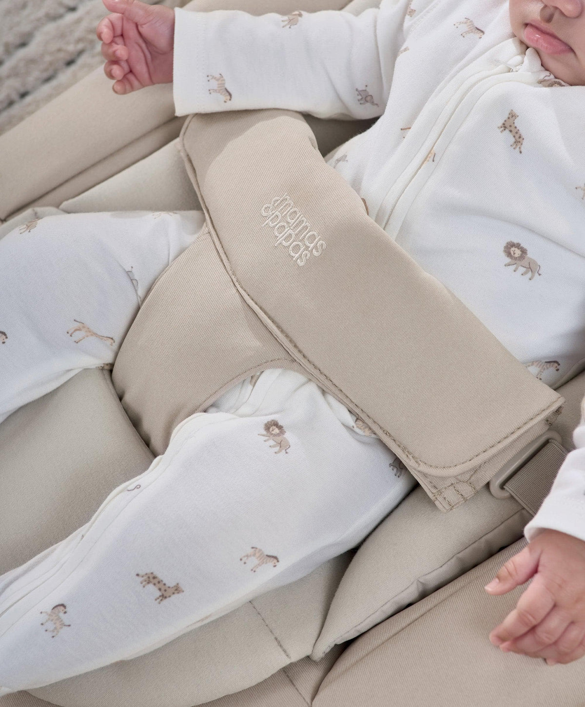 Beige bouncer harness close-up with white sleeper featuring tiny animal prints