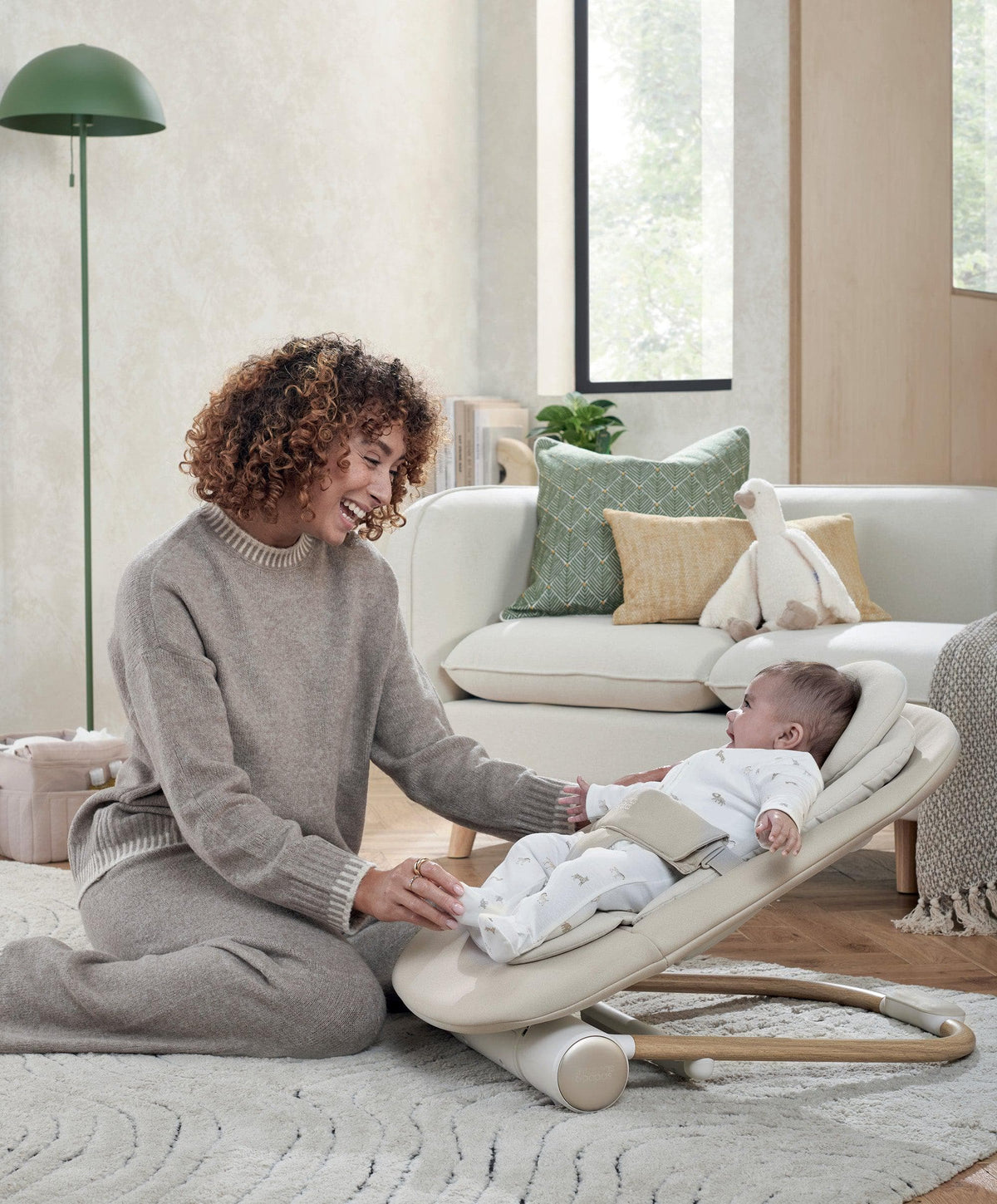 Baby cashmere bouncer seat, beige with infant inside, parent interacting
