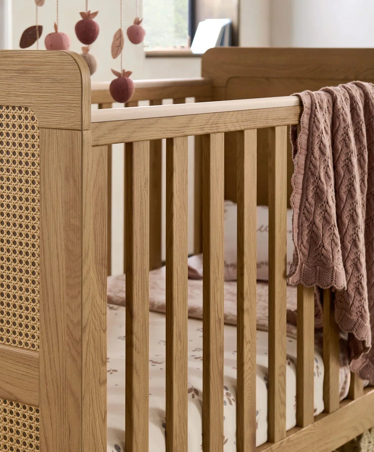 Wood cotbed with vertical slats and rattan side panel, open railing design