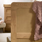 Cotbed corner with woven rattan panel inset and solid wood frame, blanket drape