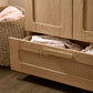 Rattan-style wardrobe open with sliding mesh drawer and folded linens inside