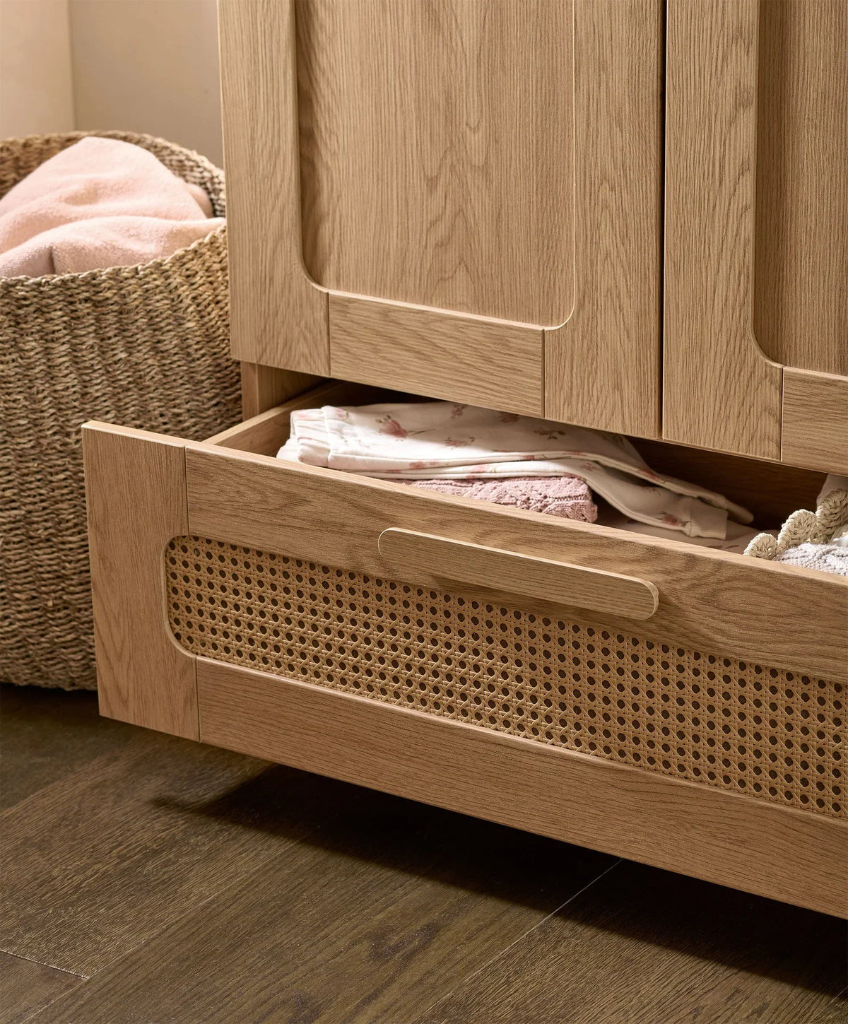 Rattan-style wardrobe open with sliding mesh drawer and folded linens inside