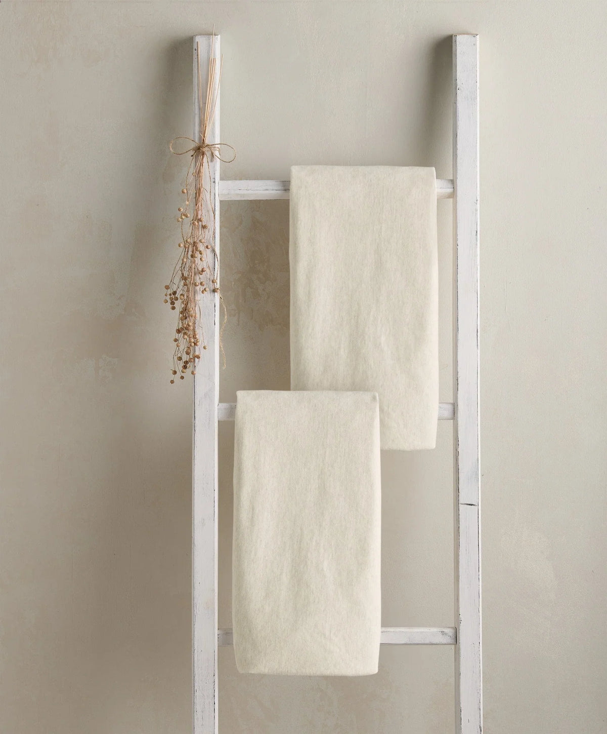 Cotbed fitted sheets (2-pack) in oatmeal, folded on bed frame