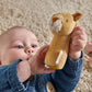 Lion mini rattle held in a hand, tan plush with white muzzle and yellow nose
