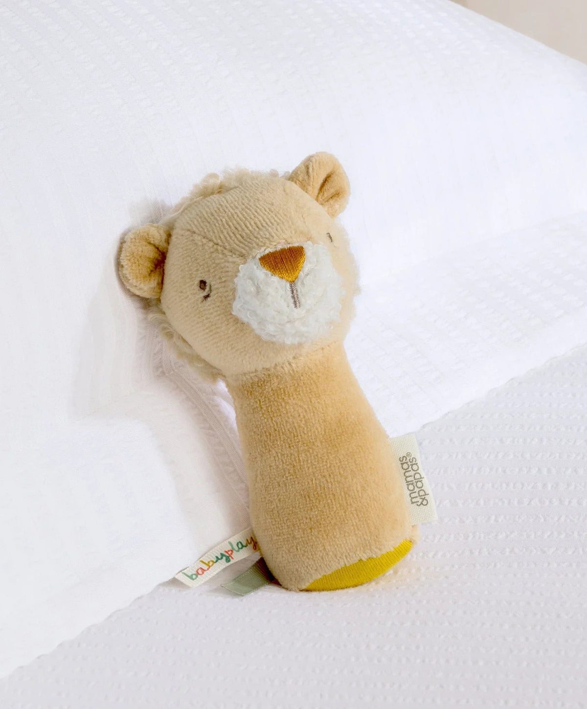 Lion mini rattle plush with tan body, white muzzle, and yellow triangle nose patch