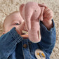 Pink elephant mini rattle held by baby hands against denim outfit