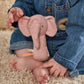 Pink elephant mini rattle with ribbon tag in baby hands over rug