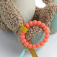Plush hippo activity toy detail: orange beaded ring with fabric tags on paw