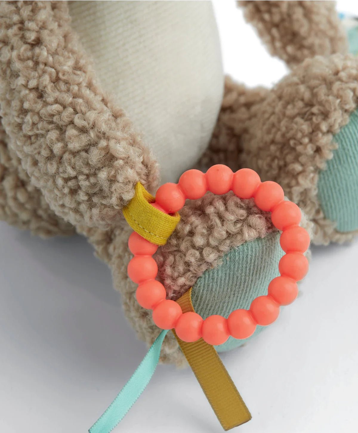 Plush hippo activity toy detail: orange beaded ring with fabric tags on paw