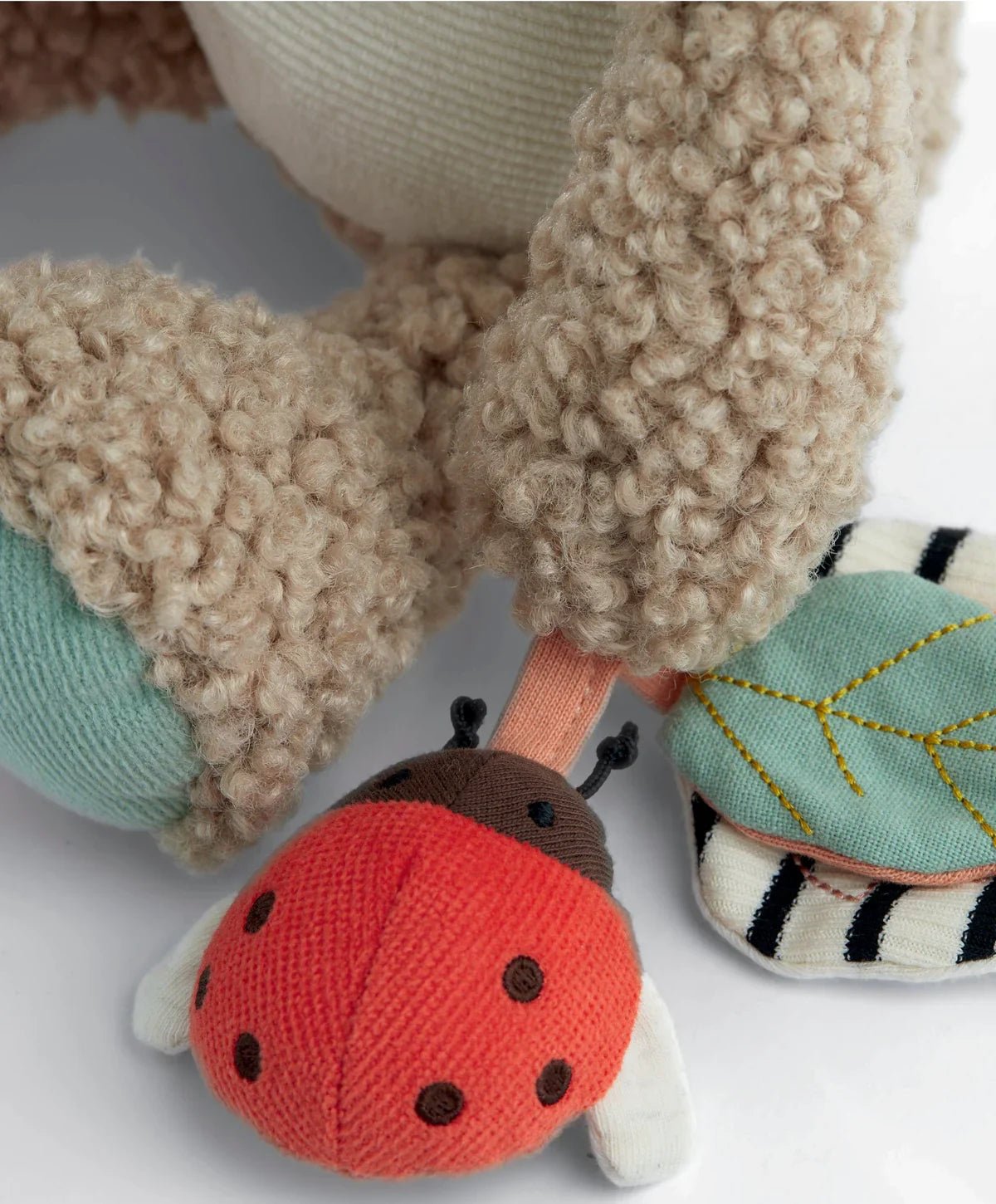 Plush hippo activity toy close-up with ladybug plush and teal fabric paw pads