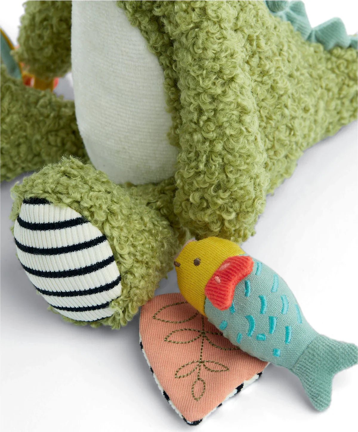 Plush green crocodile toy with striped crinkle ball and colorful fish/leaf tag