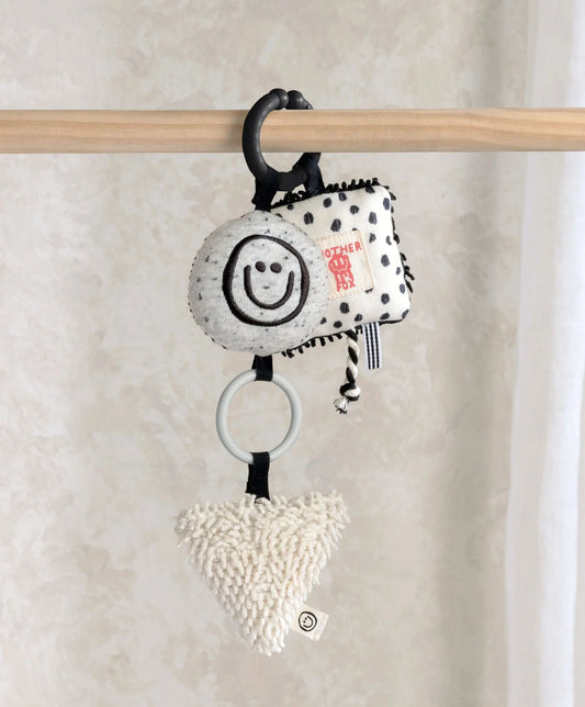Baby linkie toy with smiley face, black spots, and cream heart plush charm