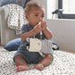 Baby holding a plush zebra activity toy with striped body and ring teether