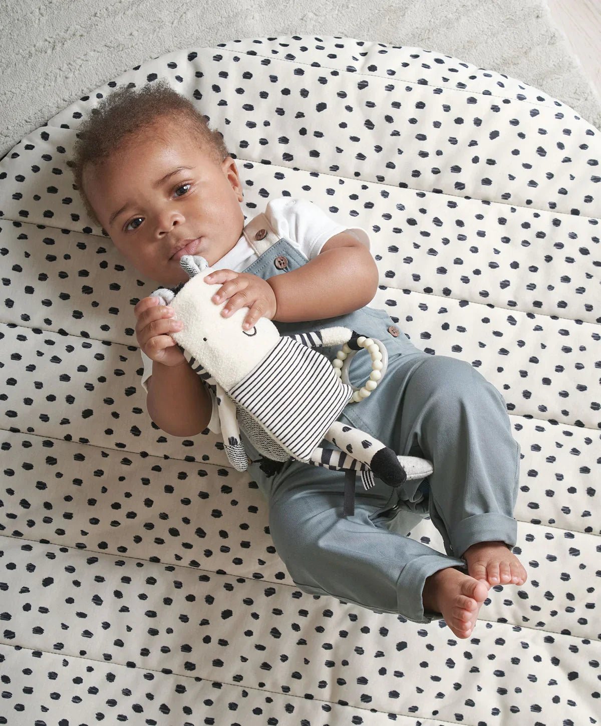Plush zebra activity toy with striped legs and fabric ring teether, held by baby