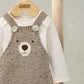 Knitted bear dungarees with tan-brown bib and shoulder straps over cream long-sleeve bodysuit