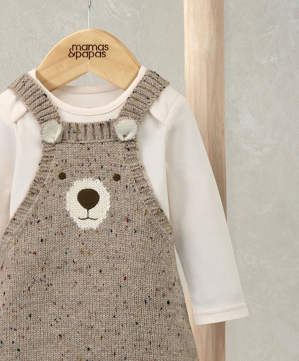 Knitted bear dungarees with tan-brown bib and shoulder straps over cream long-sleeve bodysuit