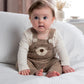 Baby wearing brown knitted bear dungarees with cream long-sleeve bodysuit, front bear face
