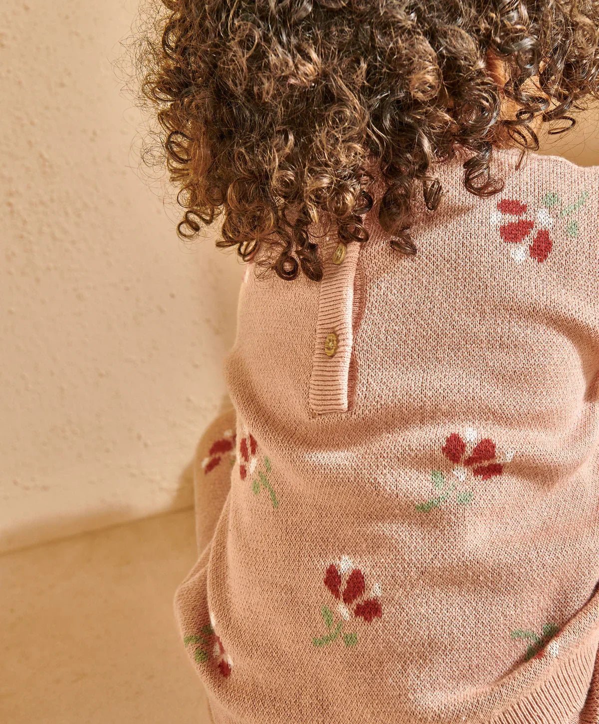 Close-up of blush floral knit top with button placket and ribbed collar