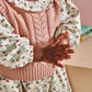 Pink cable-knit vest and floral dress with frilled collar, close-up