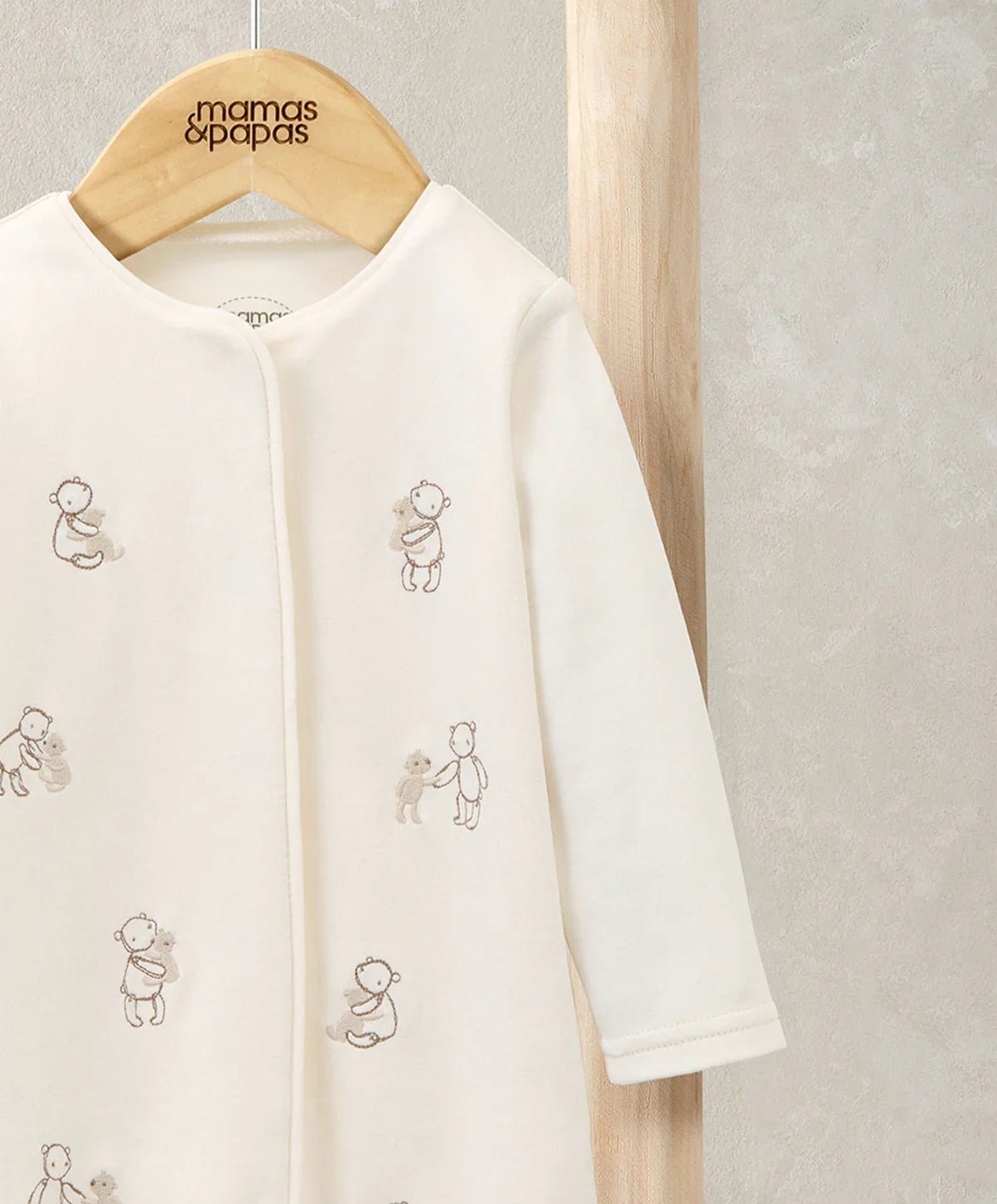 Cream romper with embroidered bear characters on chest and full-length legs