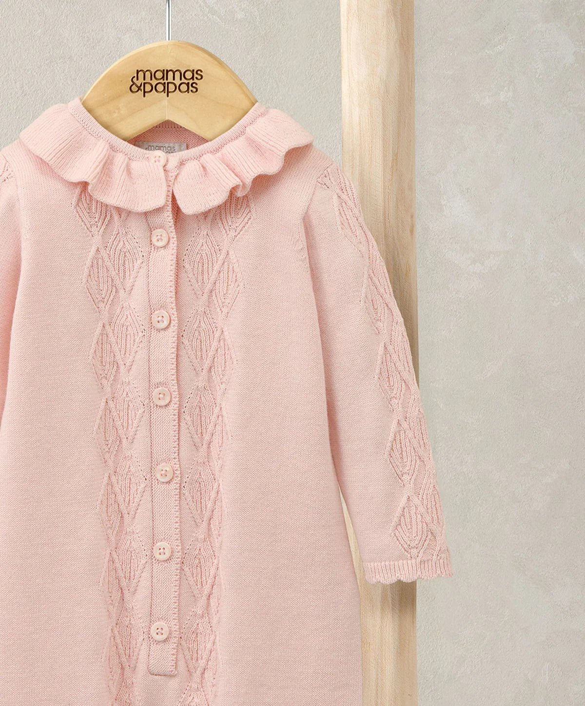 Pink knitted romper with frill collar and diamond-textured button placket