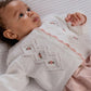 Baby wearing white embroidered cable knit cardigan with pink button placket and floral motifs