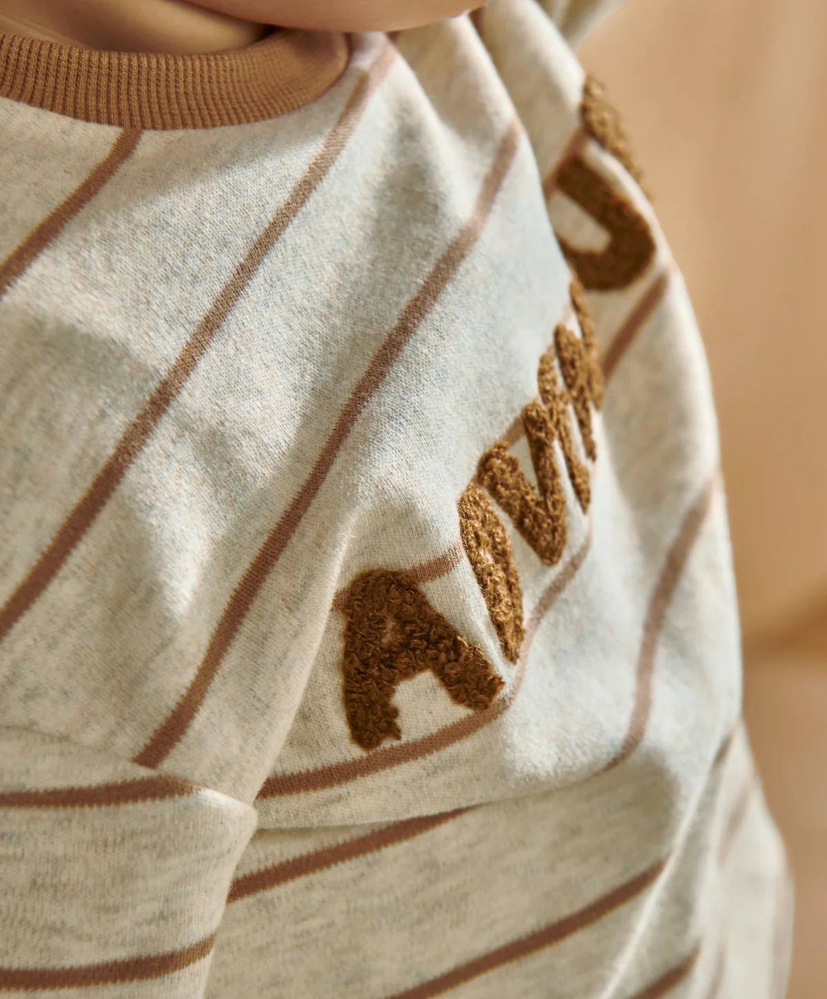 Cream striped t-shirt close-up with textured brown Adventure lettering