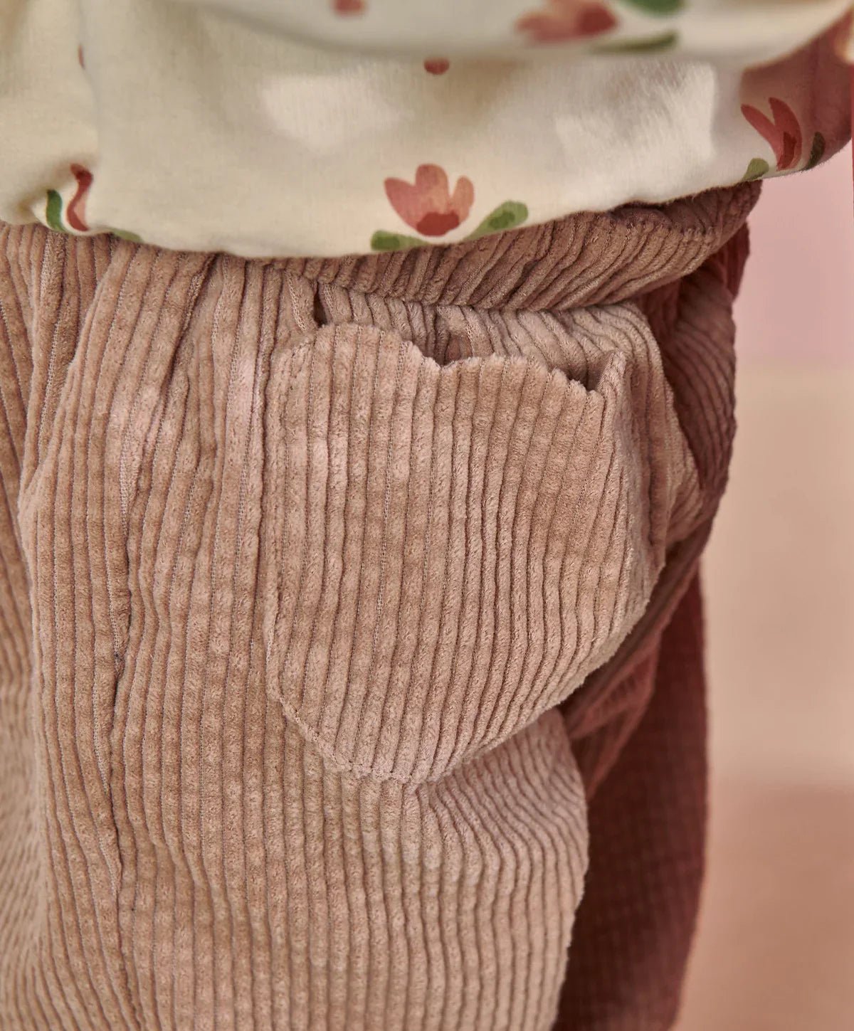 Pink cord trousers close-up of elastic waistband and side seam pocket