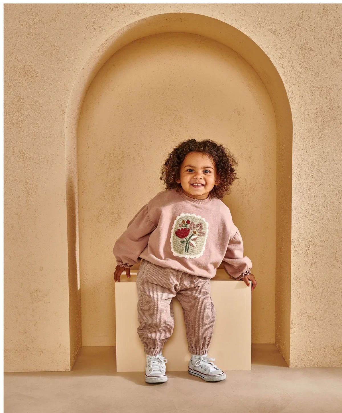 Pink sweatshirt with floral chest appliqué and balloon sleeves, worn with matching joggers