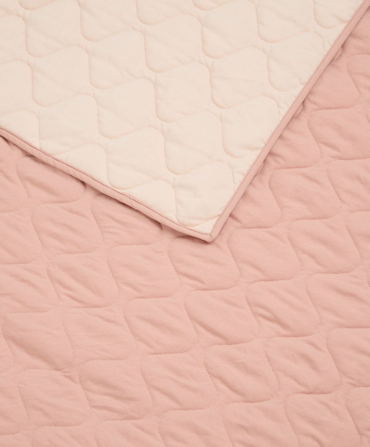 Baby quilt close-up of pink and cream stitched edges with quilted texture