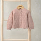 Pink knit cardigan with button front, textured cable pattern, ribbed cuffs and collar