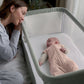Pink zip-front swaddle sleeping bag on a baby in an open crib
