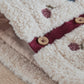 Cream sherpa with burgundy placket, embroidered motifs, and round wooden button