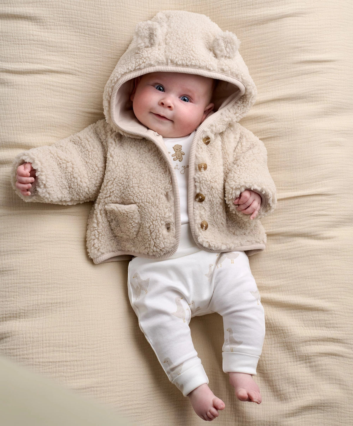 Cream hooded borg jacket with snap front, two chest pockets, teddy texture.
