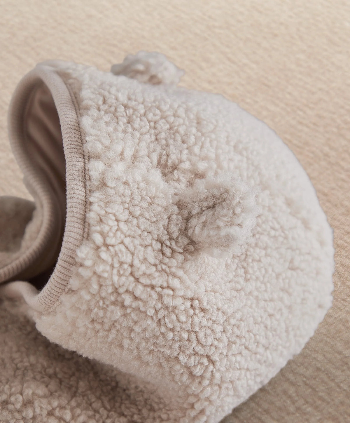 Cream borg hood with teddy-pile texture and ribbed trim.