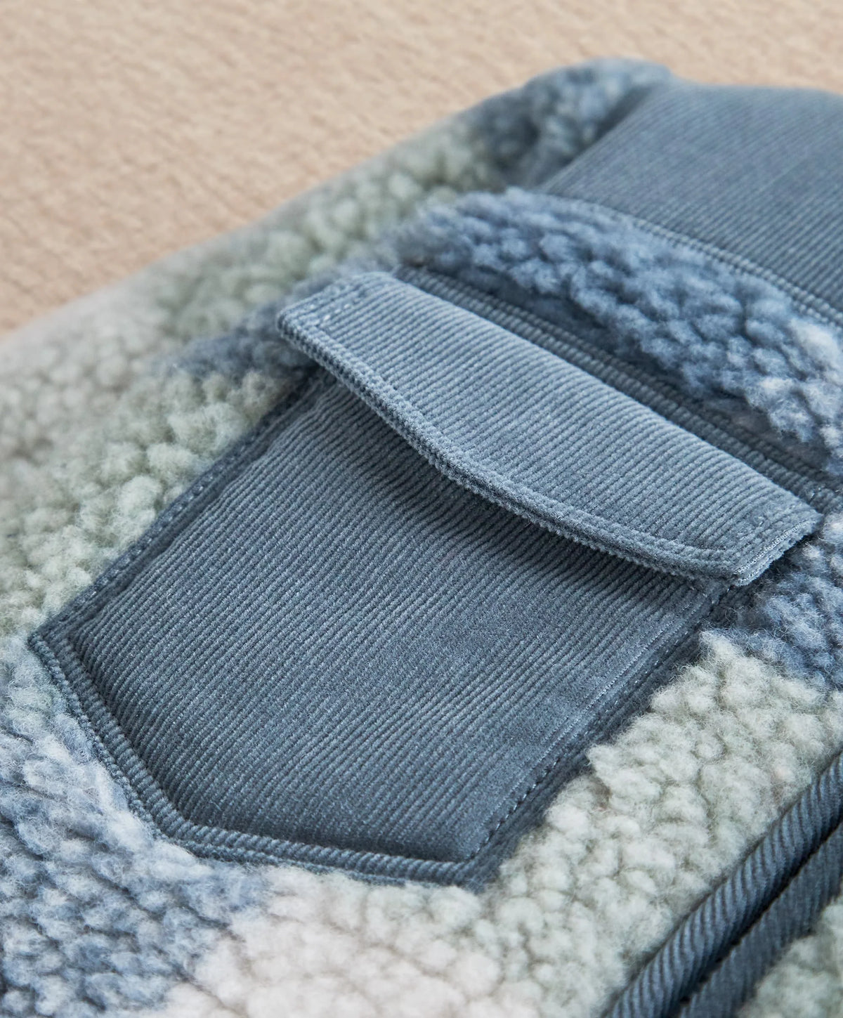 Fleece pramsuit chest patch pocket detail with blue corduroy flap and edging