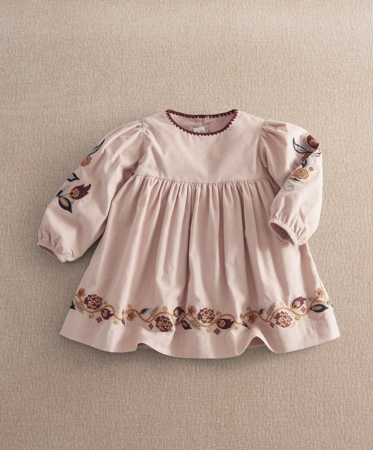 Light pink embroidered corduroy dress with long puff sleeves and floral hem border