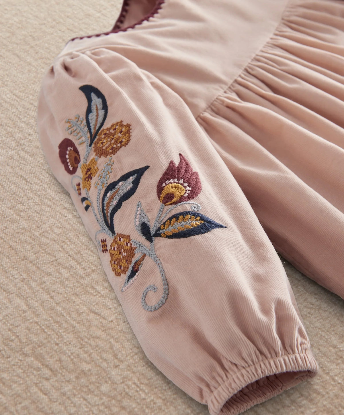 Light pink corduroy dress sleeve with floral bird embroidery and gathered puff cuff