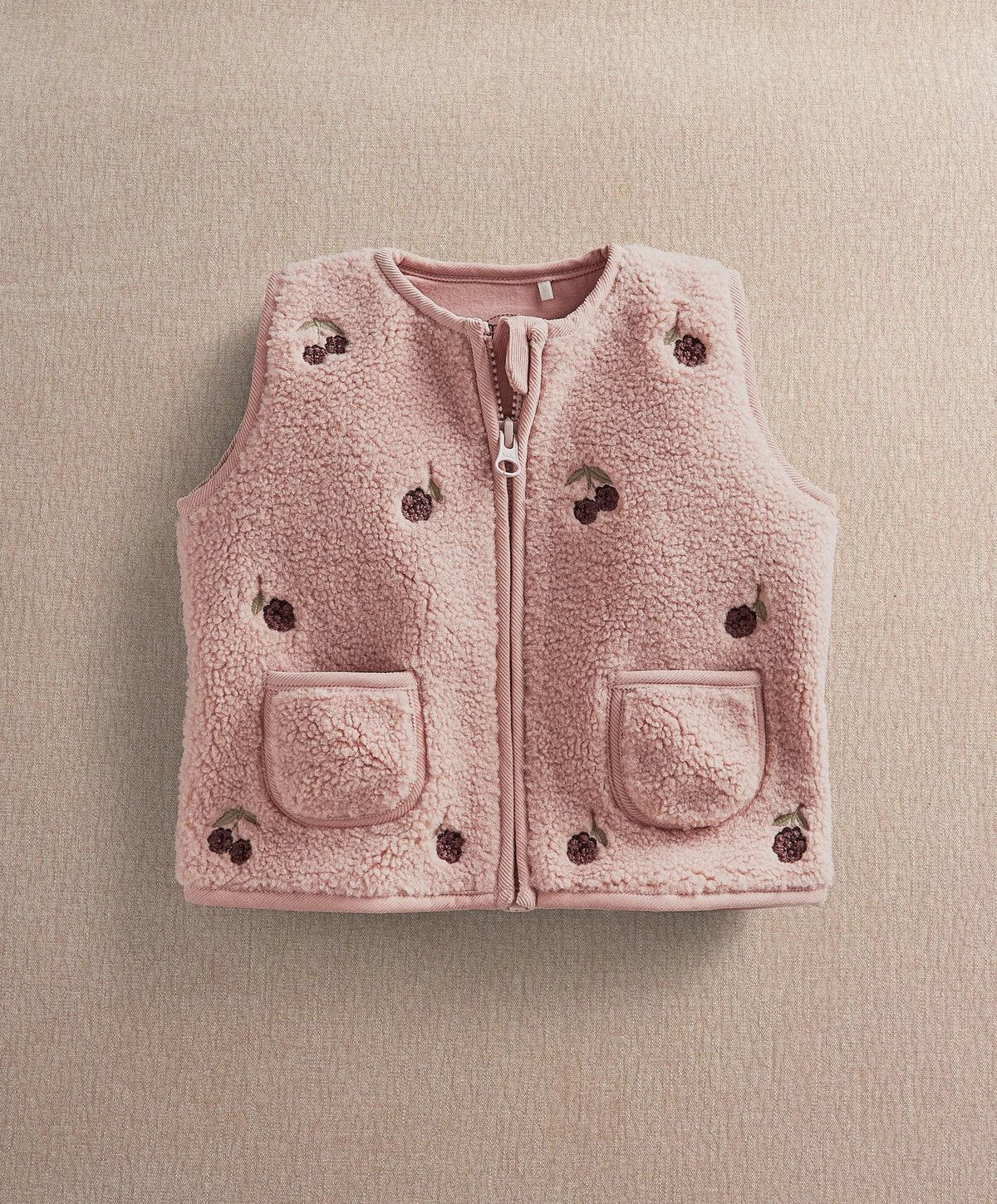 Pink fleece gilet with front zipper, two flap pockets, embroidered dot patches