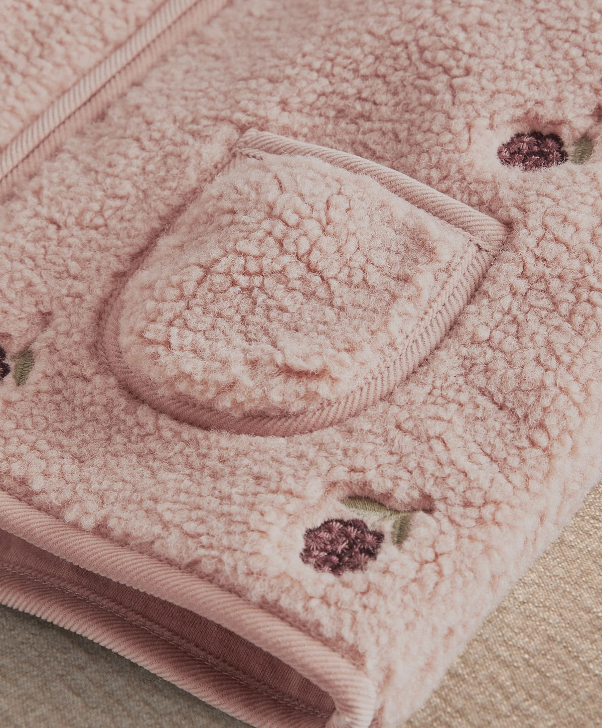 Pink fleece gilet close-up of embroidered chest pocket and textured trim