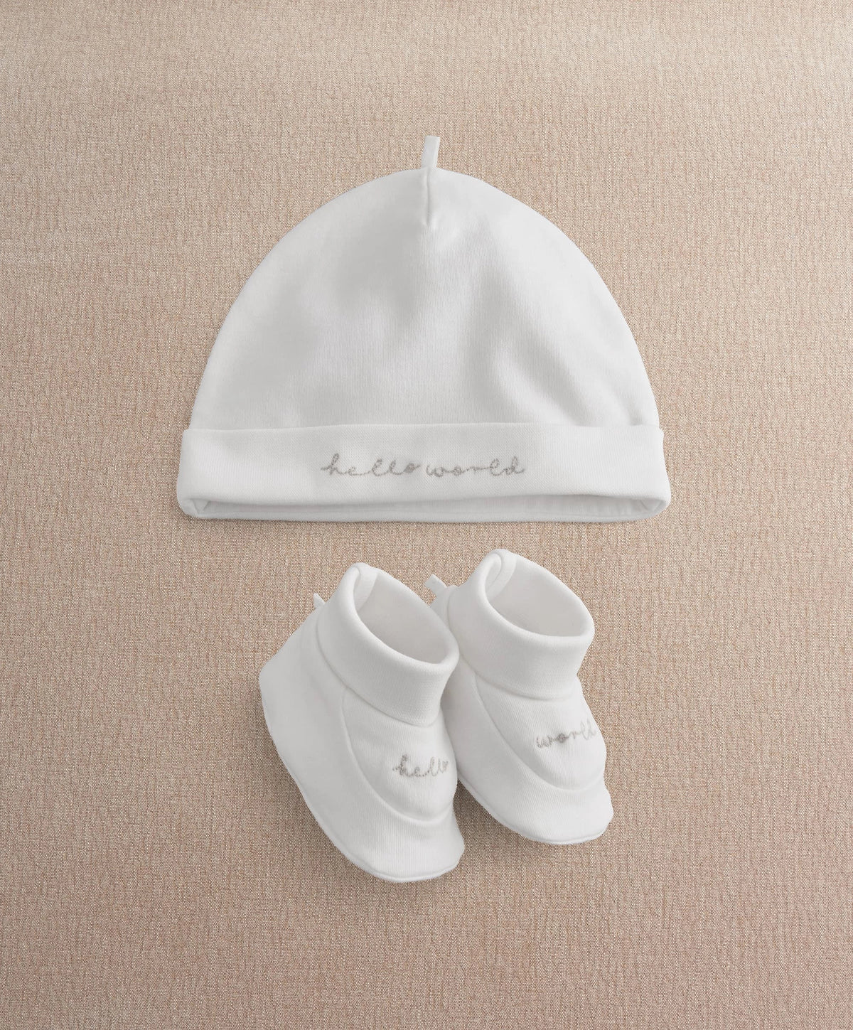 White baby beanie hat and booties set with cursive text accents
