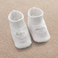 Pair of white baby booties with cursive text logo on side