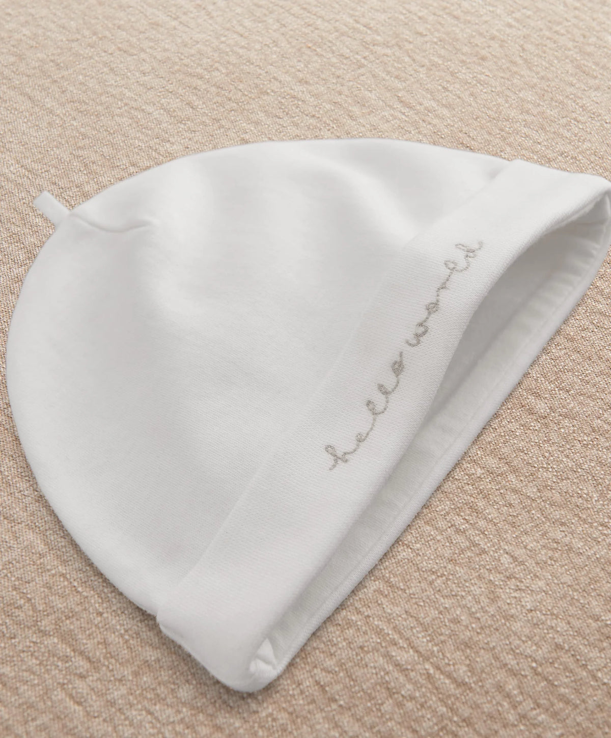 White baby hat with curved script embroidery on folded side