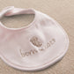 Pink baby bib with rounded neck, embroidered bear and 'born in 2027' text