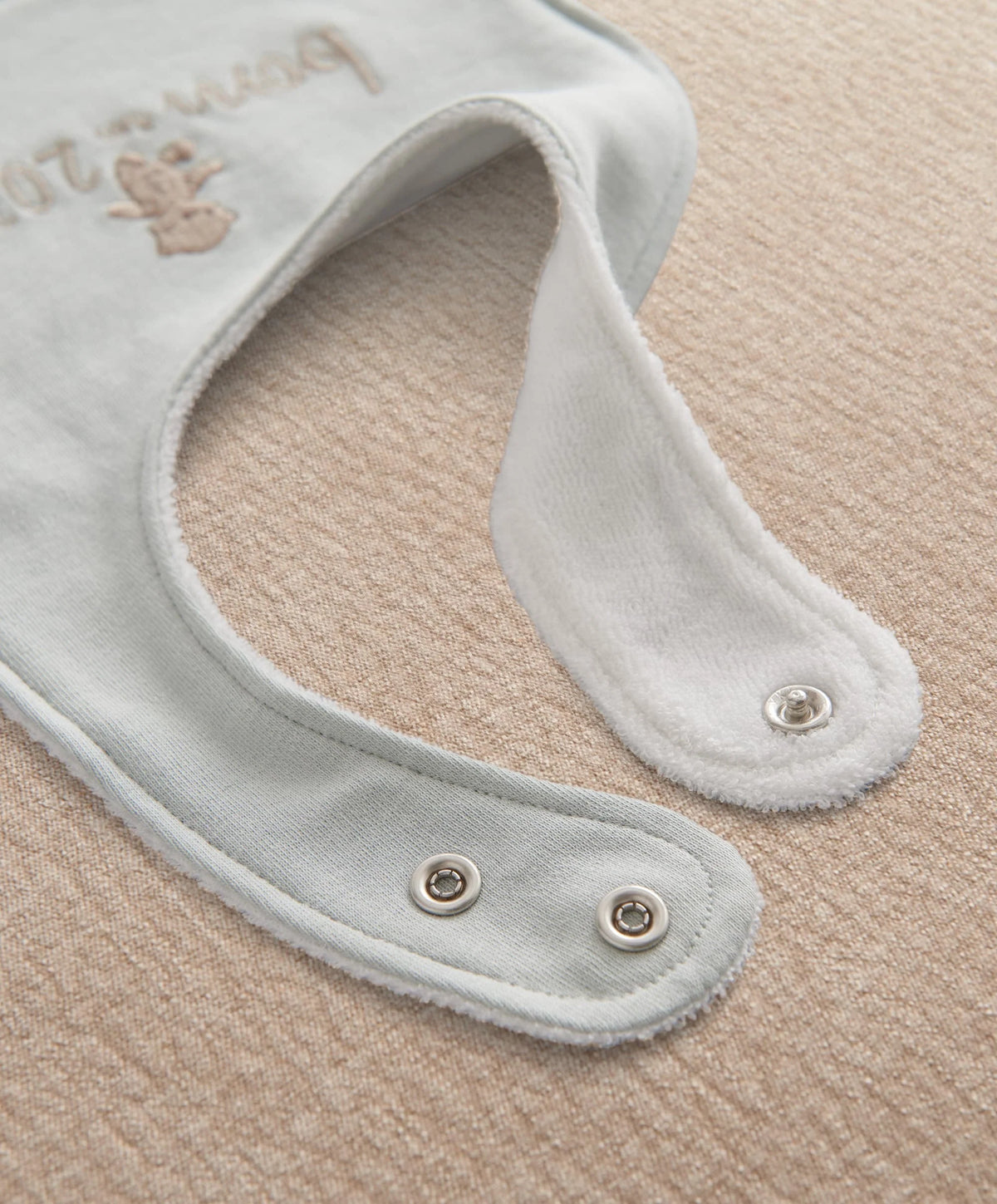 Light blue baby bib with snap buttons and curved neckline trim